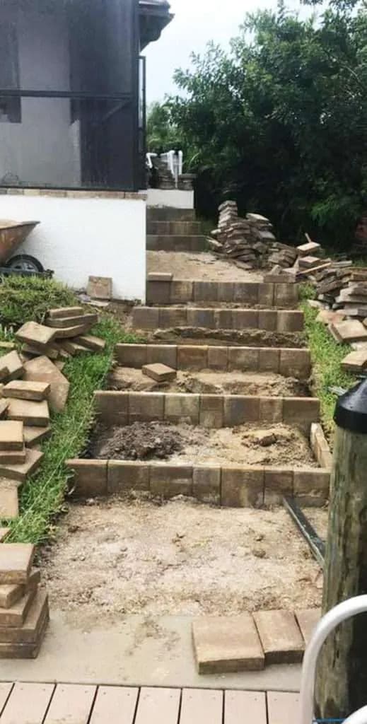 Stone steps under construction in a garden with stacked bricks and landscaping work.