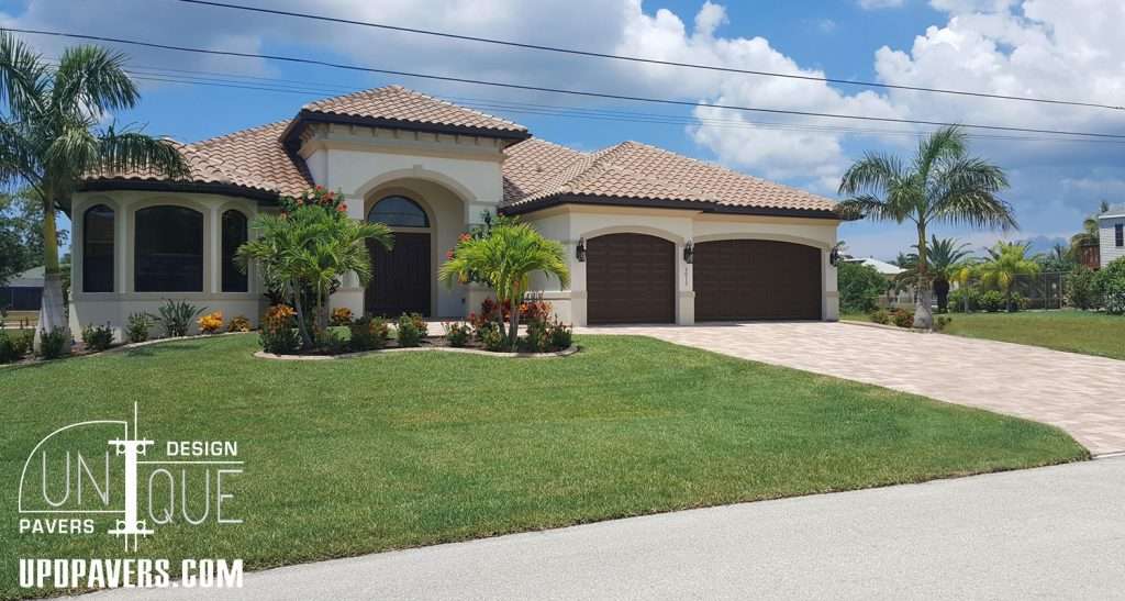 Modern single-family home with a tile roof, landscaped yard, and paver driveway. Unique Pavers design.