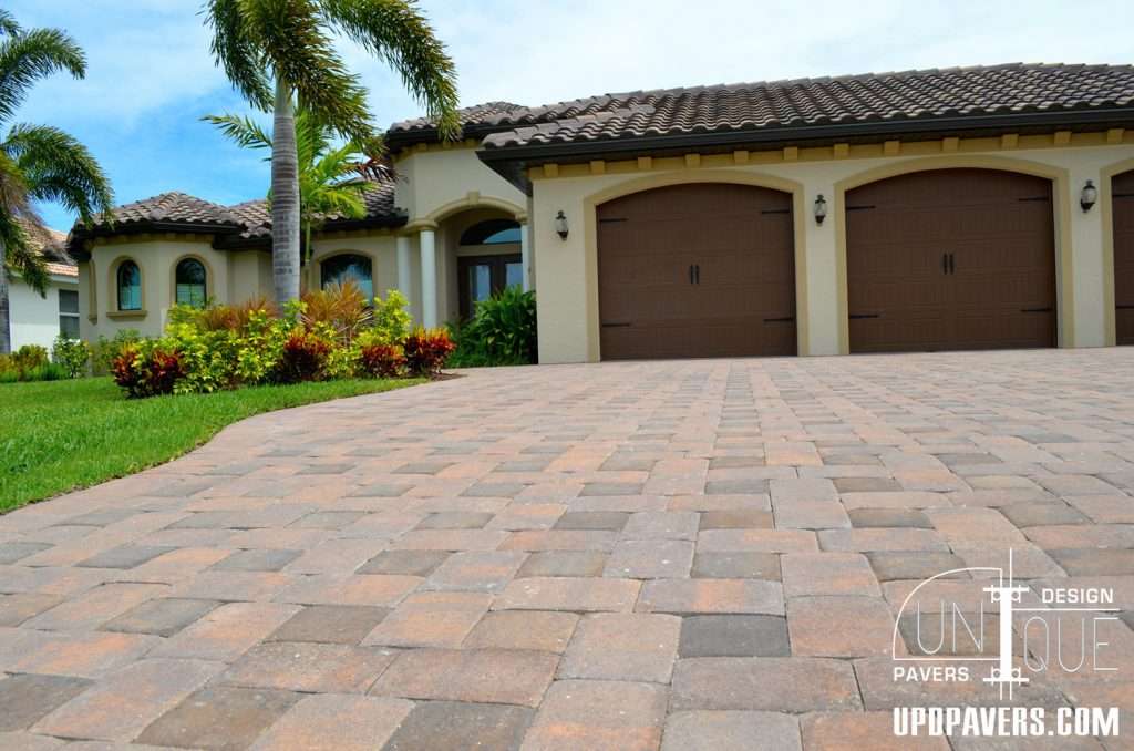 Elegant home with a paved driveway and lush landscaping under clear blue skies.