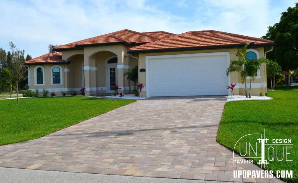 Modern single-family home with a paved driveway, tropical landscaping, and decorative stone accents.