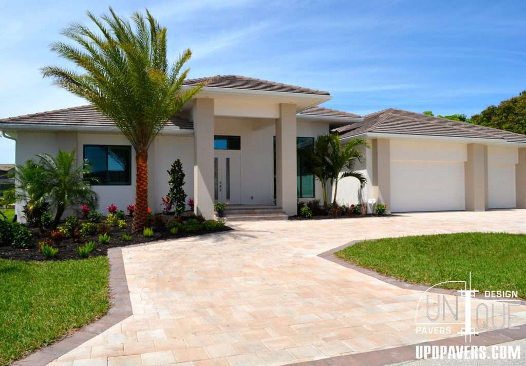 Modern luxury home exterior with landscaped garden and driveway, featuring palm trees.