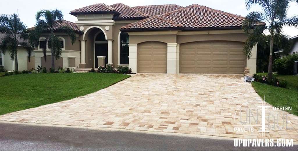 Luxury home with a paver driveway and landscaped yard in a sunny neighborhood.