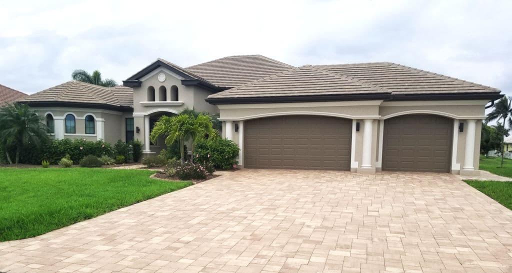 Modern single-family home with a paved driveway, lush greenery, and decorative landscaping.