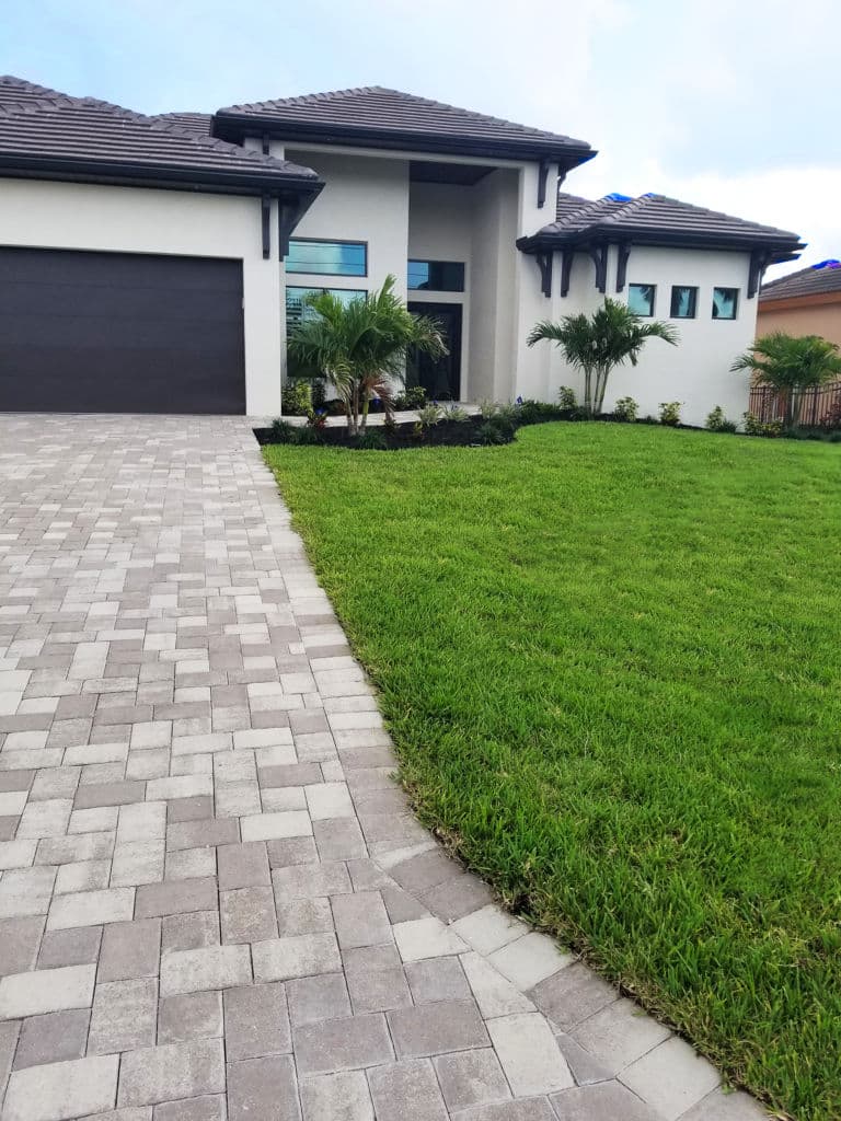 Modern house with driveway, landscaping, and green lawn in a sunny neighborhood.