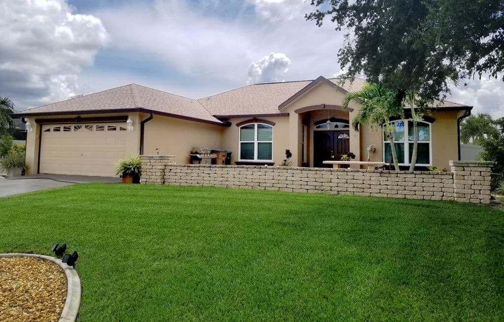 Single-story home with a manicured lawn, stone accents, and a welcoming porch.
