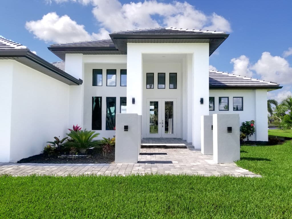 Modern white house with large windows, manicured lawn, and stylish entrance.
