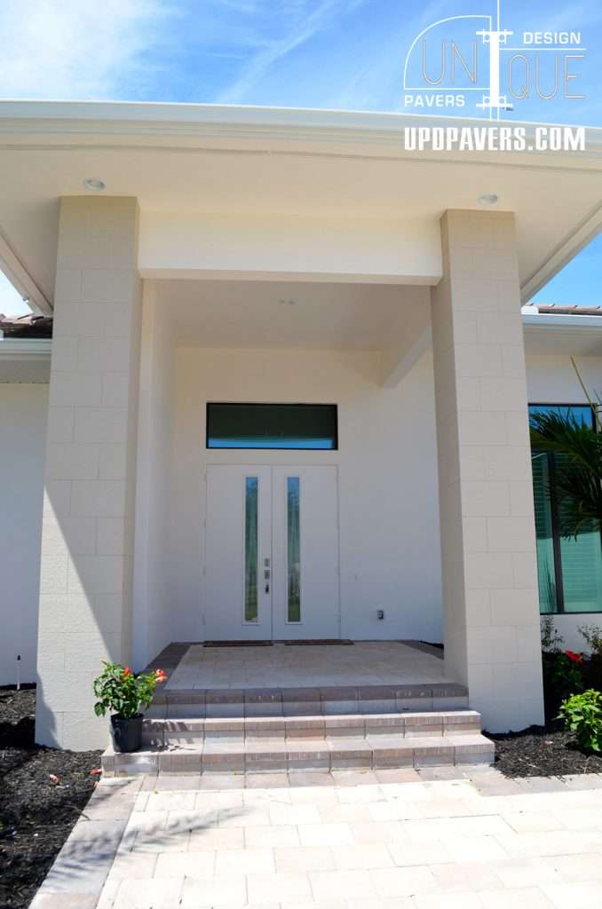 Modern entryway with double doors, elegant stone steps, and landscaped borders. Unique Pavers design.