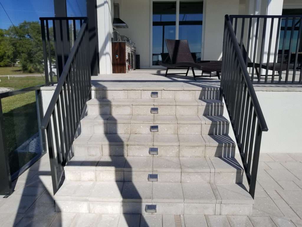 Modern outdoor staircase with black railings and built-in step lights leading to a house.