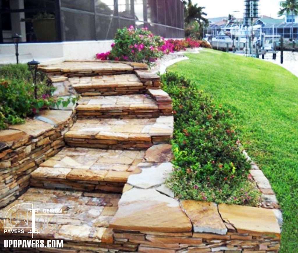 Stone steps leading to a landscaped garden with vibrant flowers and green grass.