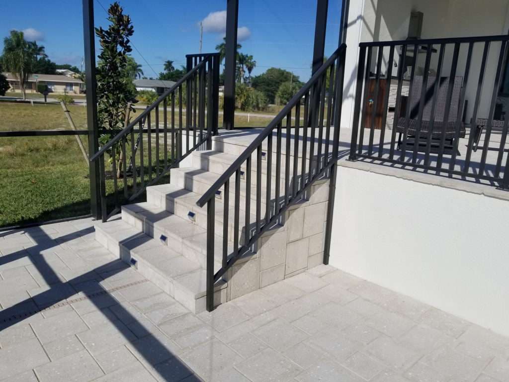 Staircase with railing leading to a patio in a residential outdoor space.