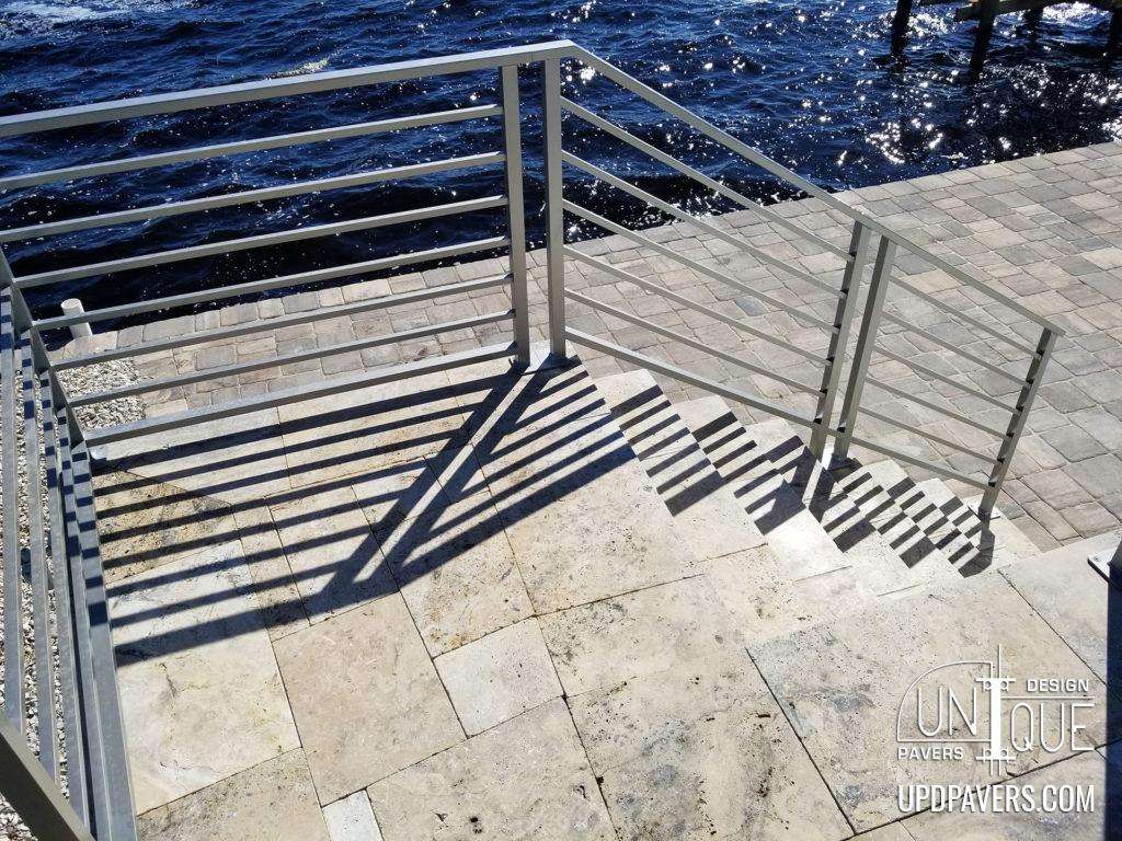 Modern stair railing on a stone pathway by water, showcasing design and functionality.