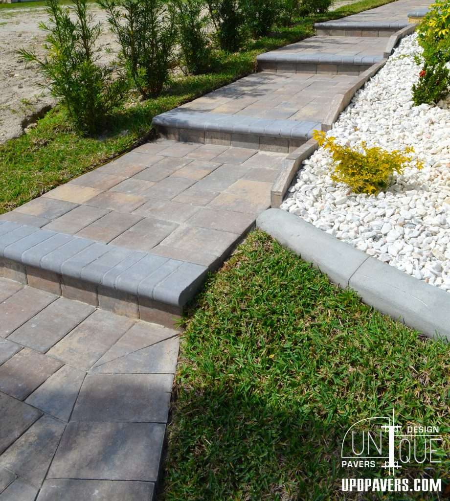 Paved walkway with curved design, bordered by greenery and decorative stones. Unique landscape feature.