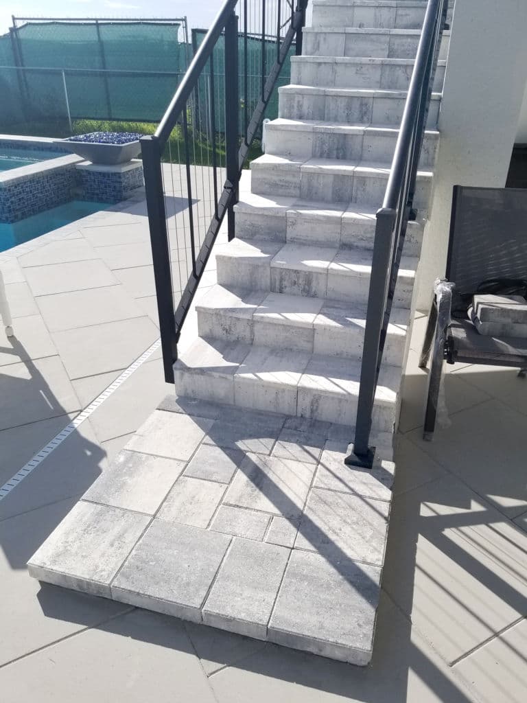 Gray stone staircase leading to pool area with modern patio design.