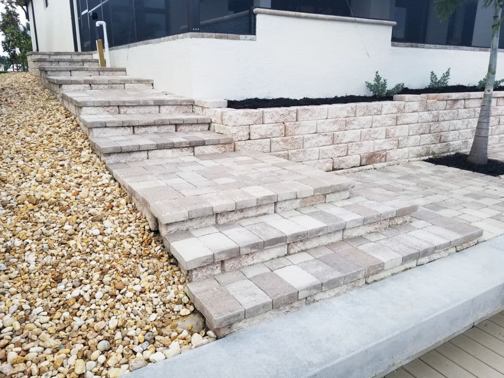 Stone paver steps leading to a landscaped area with gravel and retaining wall.