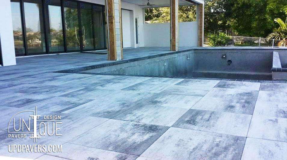 Modern outdoor patio with gray pavers and an unfilled pool area, showcasing elegant design.