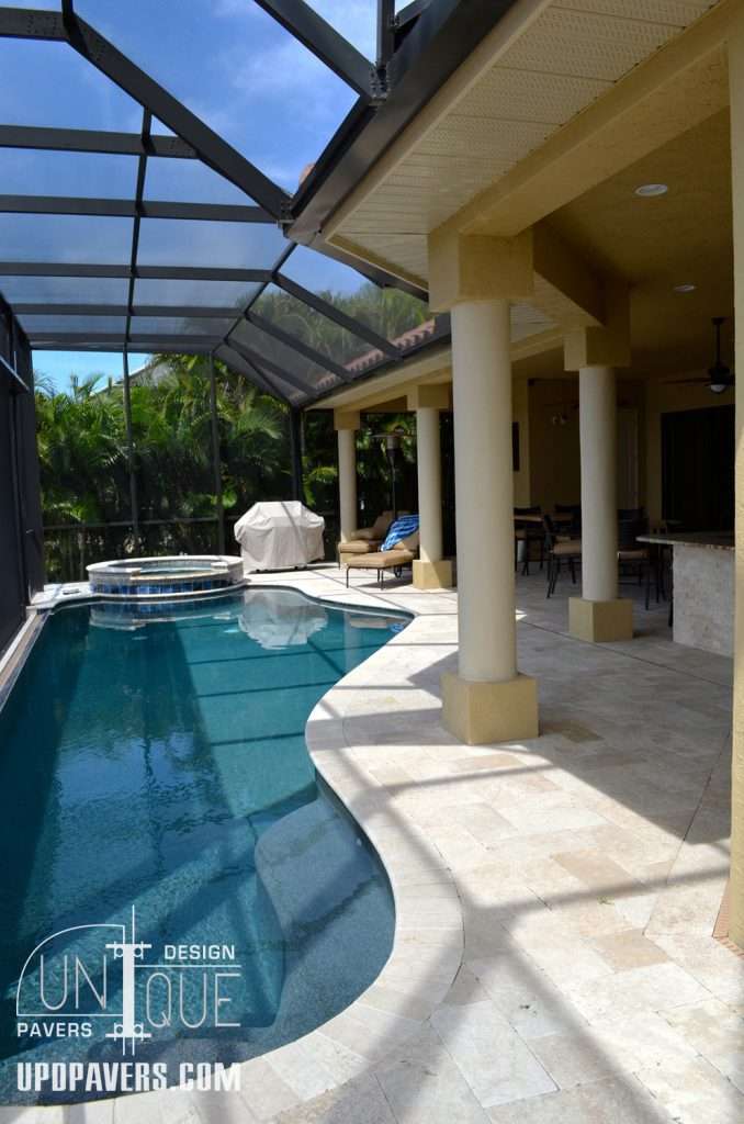 Luxurious pool area with screen enclosure, natural stone pavers, and tropical landscaping.