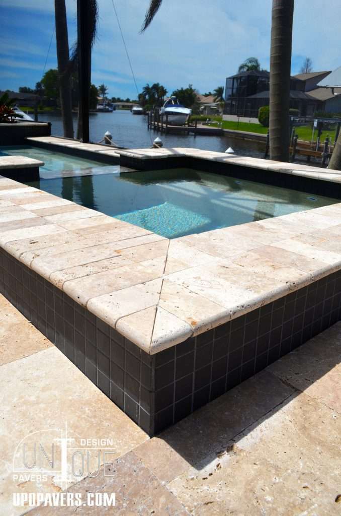 Luxury outdoor pool with travertine coping and views of waterfront homes.