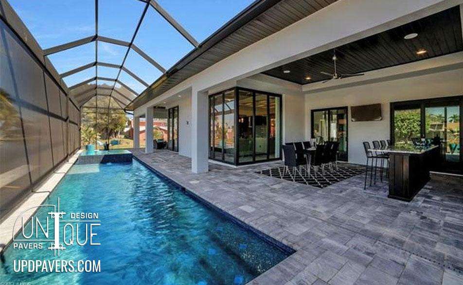 Modern outdoor living space with pool, paver patio, and dining area under a screened enclosure.