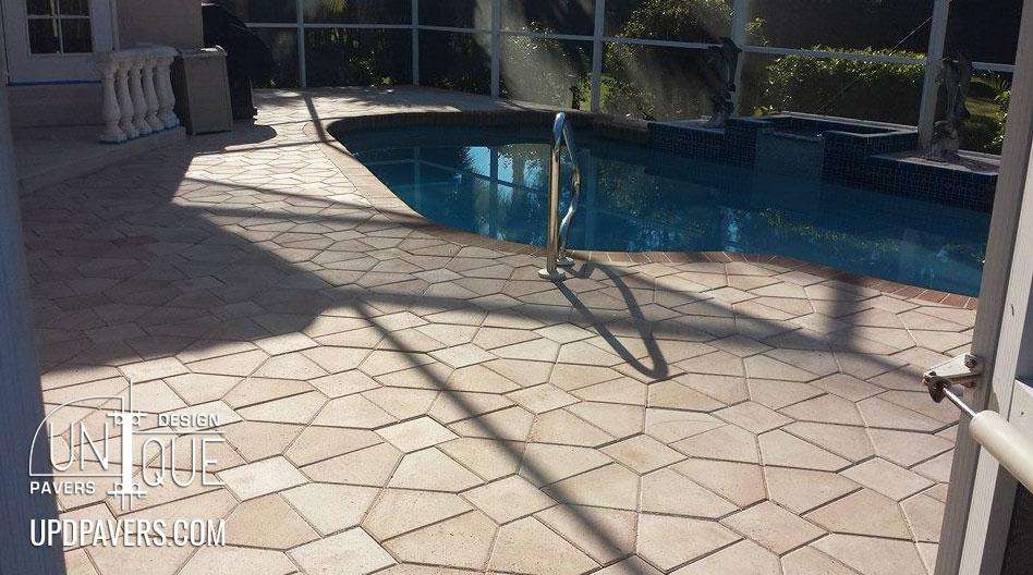 Patio with unique paver design around a swimming pool and sunlight reflections.