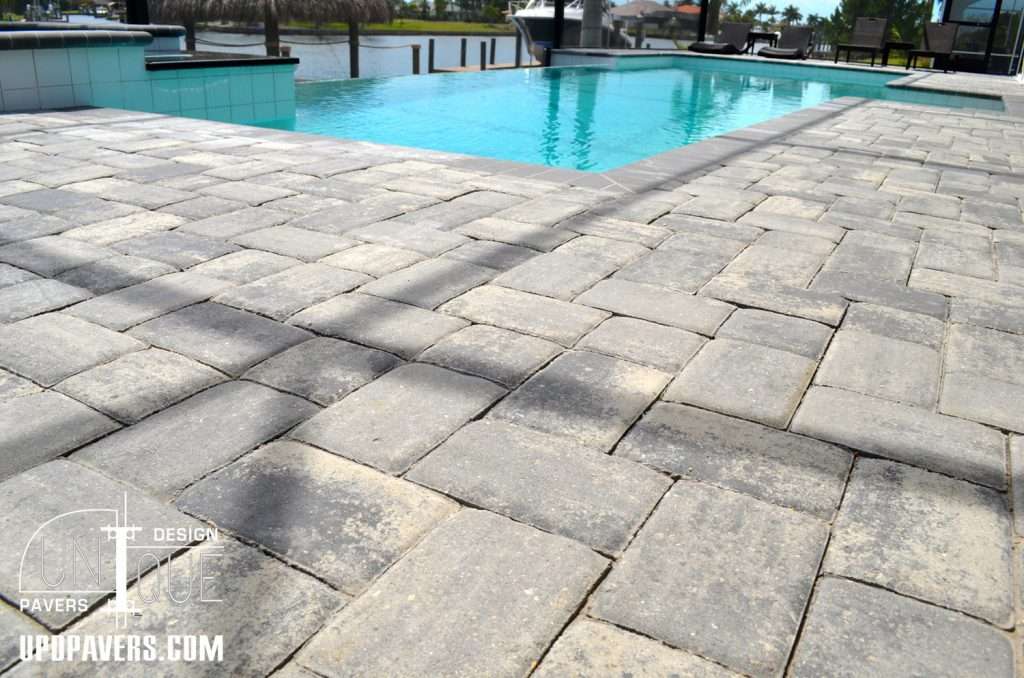 Gray interlocking pavers around a residential pool with a scenic waterfront view.