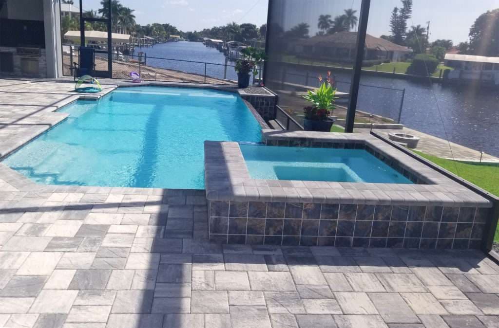 Stylish pool and spa setup with water view and outdoor patio in a sunny residential area.