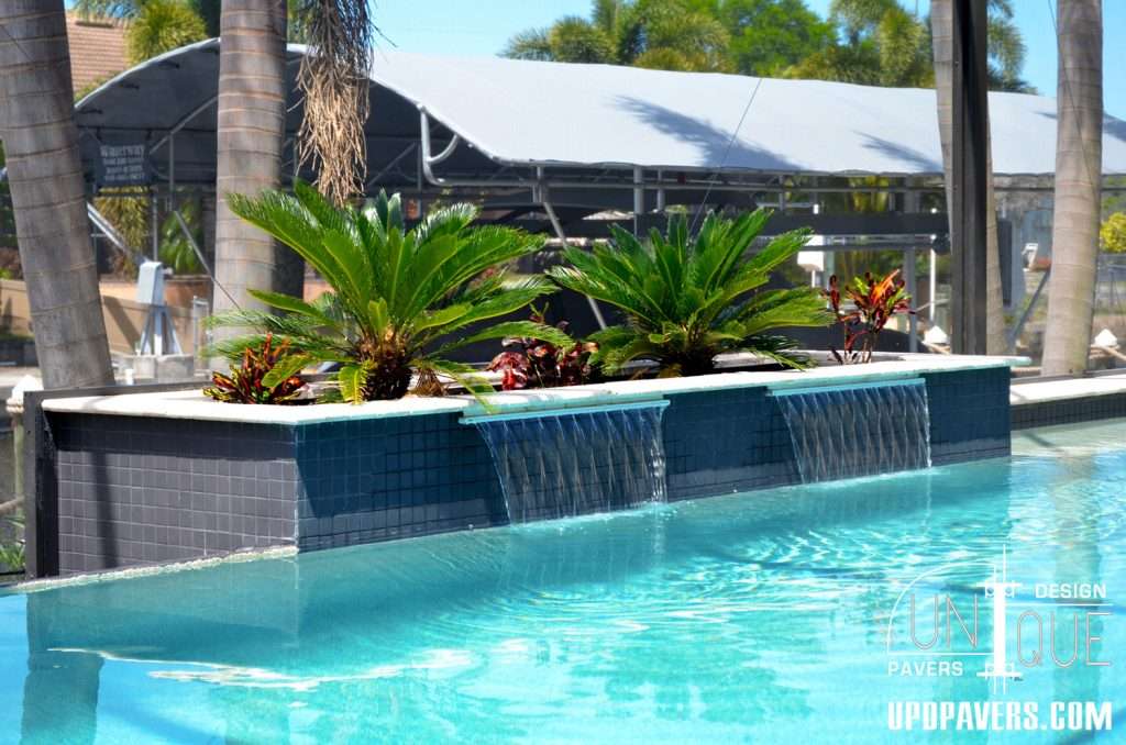 Modern pool design with water features and lush tropical landscaping.