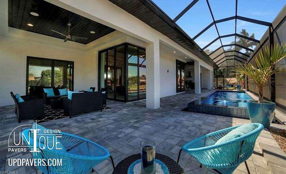 Modern patio with pool, lounge seating, and pavers in sunny outdoor setting. Unique design.