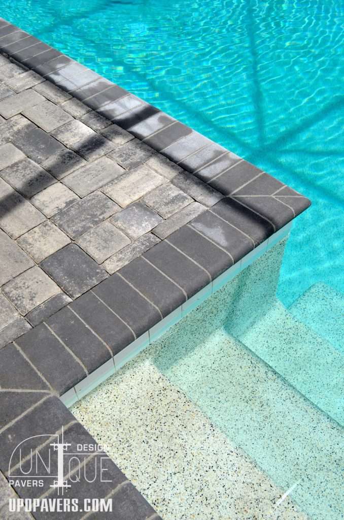 Stylish paver pool deck with a clear blue pool and modern design features.