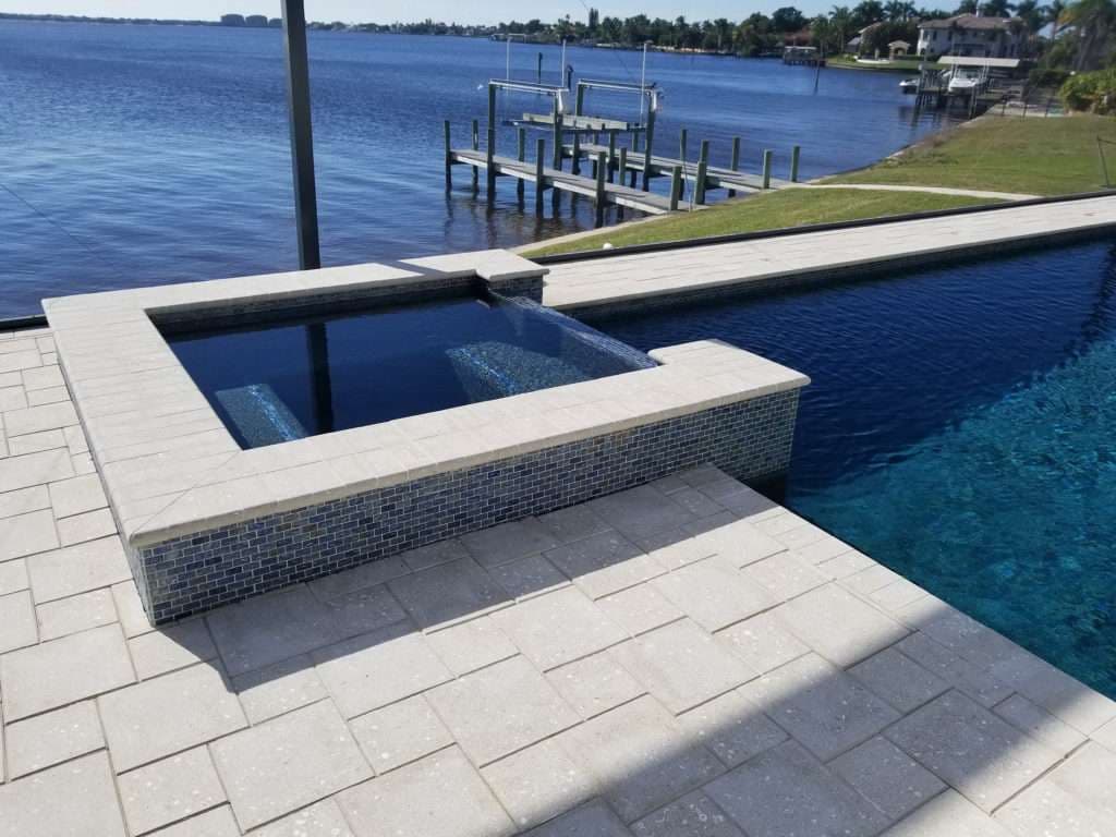 Luxury pool and spa overlooking serene lake with dock and waterfront properties.
