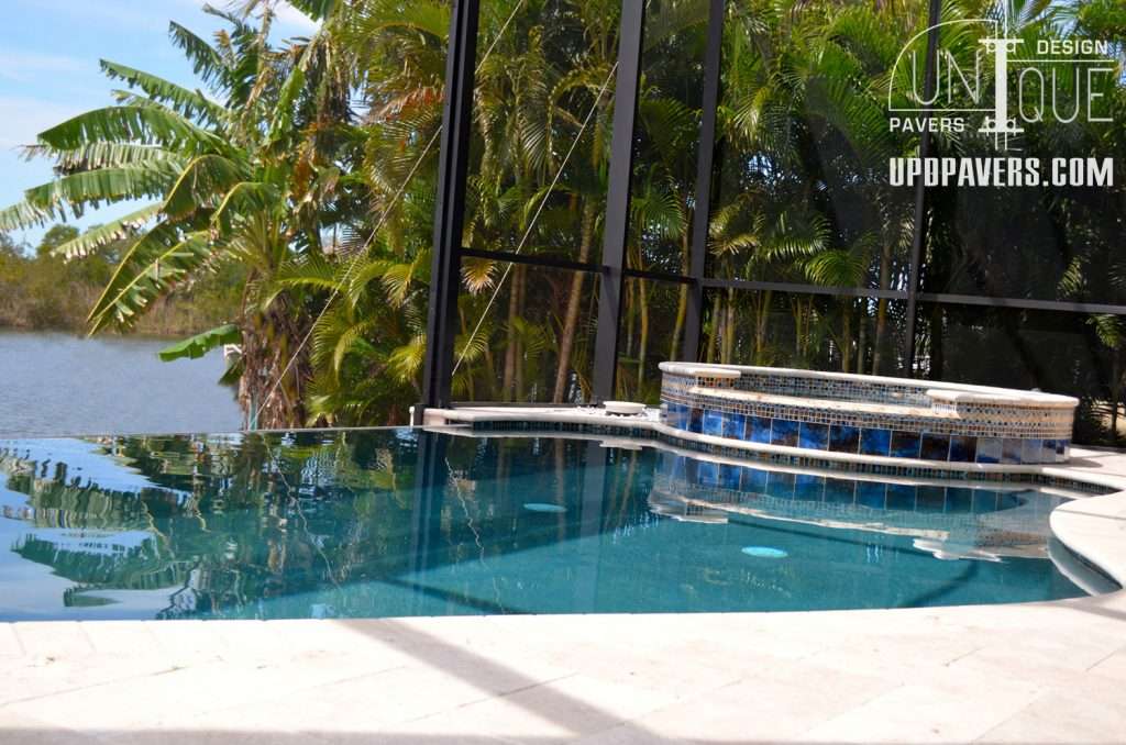 Luxury pool with spa, surrounded by tropical plants and scenic water view, in outdoor enclosure.