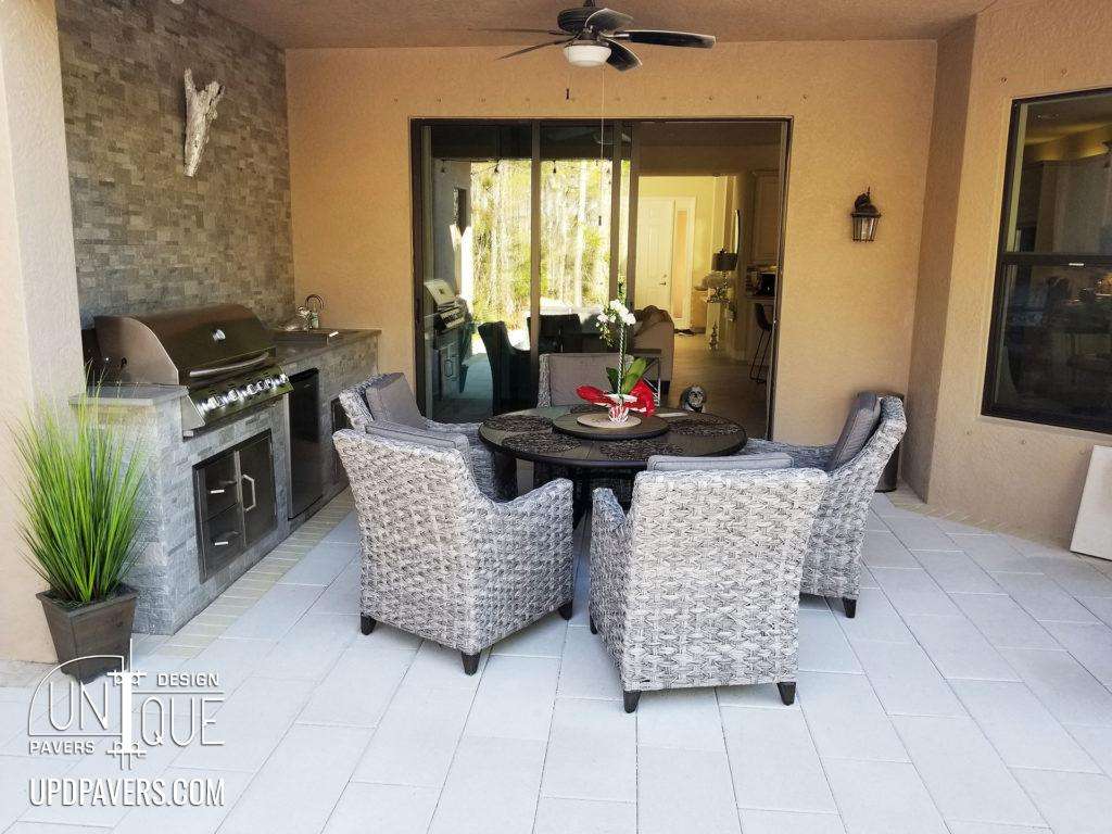 Modern outdoor living space featuring a dining table, chairs, grill, and stylish decor.