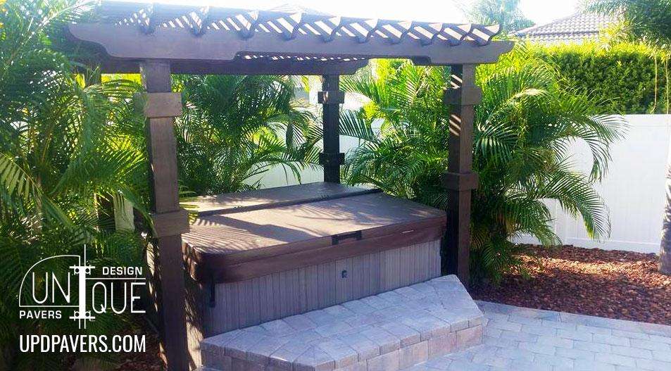 Backyard hot tub surrounded by palm trees and paver patio, designed by Unique Pavers.