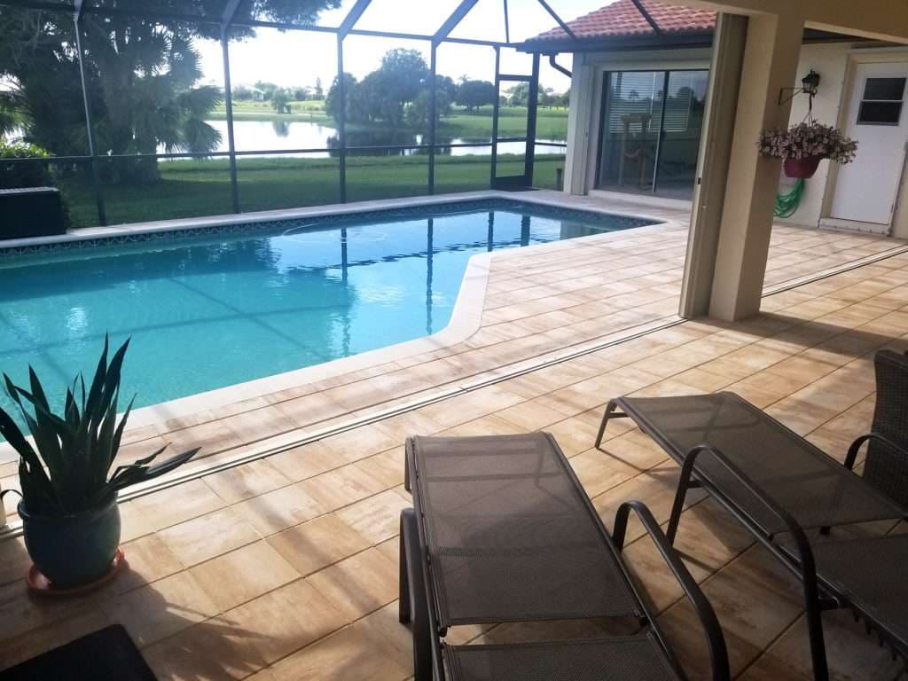 Cozy patio with a pool, lounge chairs, and scenic views of greenery and water.