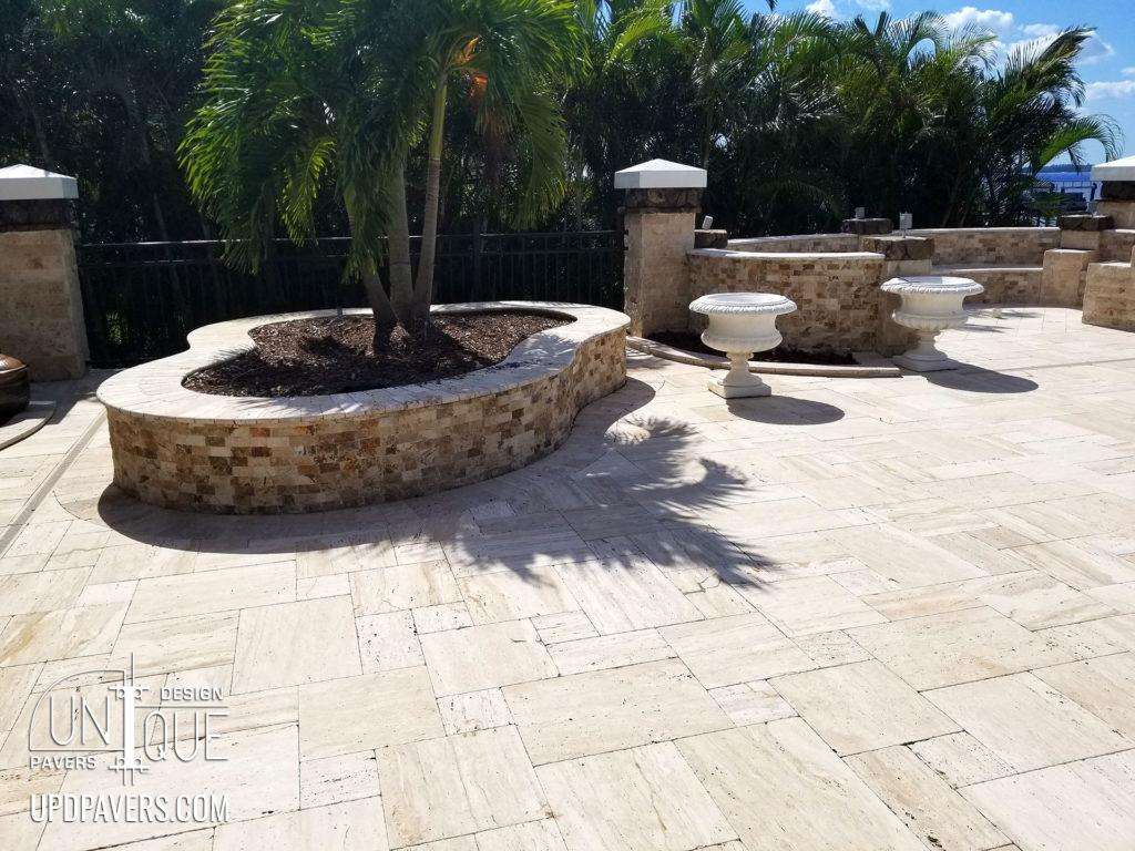 Elegant outdoor patio with stone walls, lush palm trees, and decorative planters.