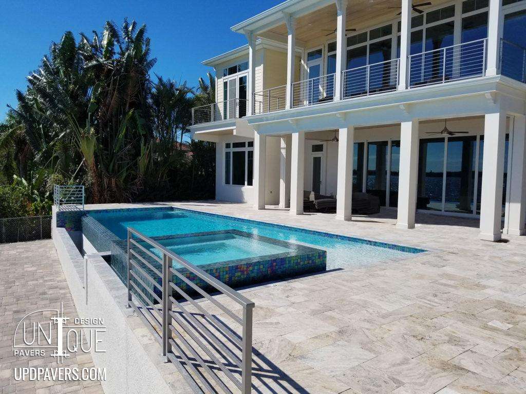 Luxurious pool and spa with modern architecture and tropical landscaping in a sunny setting.