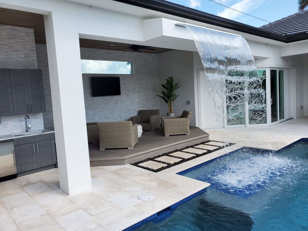 Modern outdoor patio with a water feature, pool, and cozy seating area.