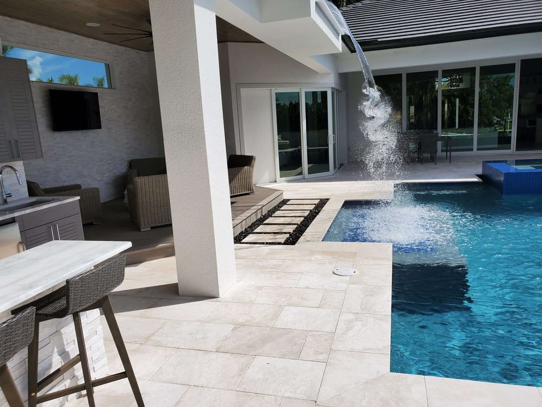 Modern backyard oasis with pool, waterfall feature, and stylish outdoor seating.