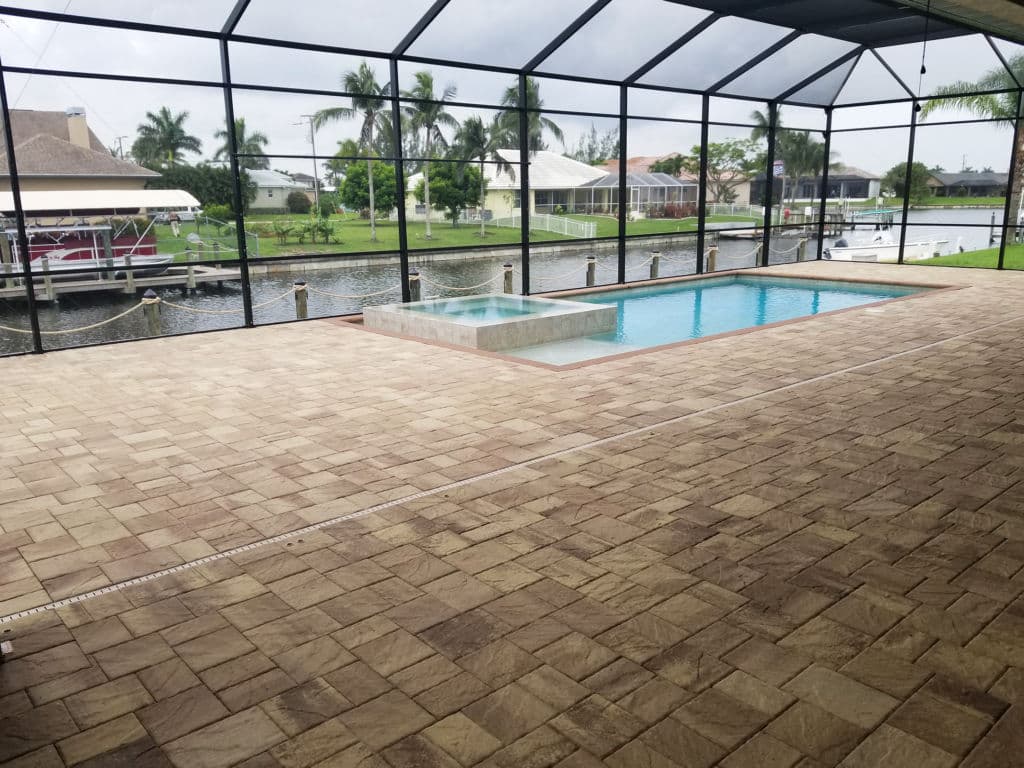Private screened pool area with spa overlooking a canal and tropical landscape.