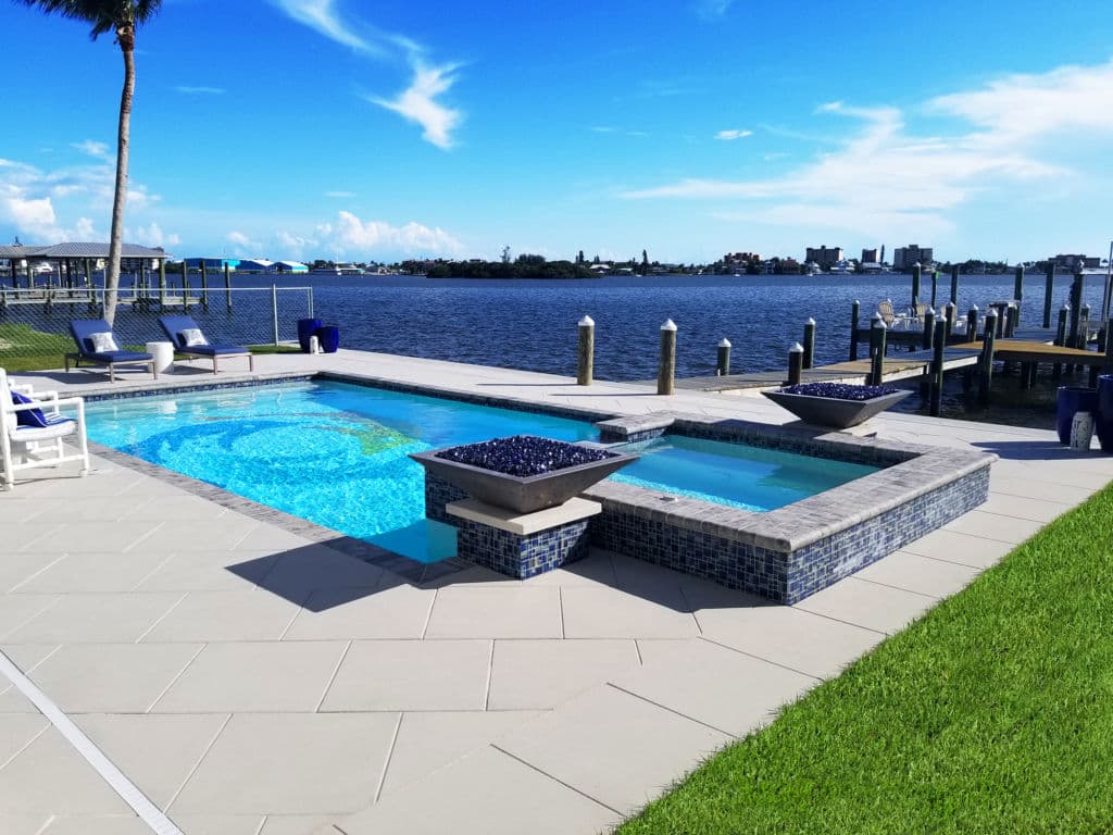 Luxury backyard pool with waterfront view, blue tiles, and relaxing lounge chairs.