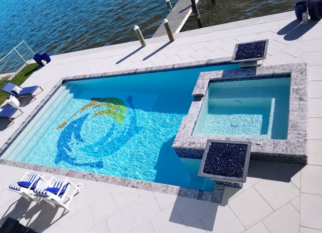 Aerial view of a modern pool with mosaic design, hot tub, and lounge chairs by the water.