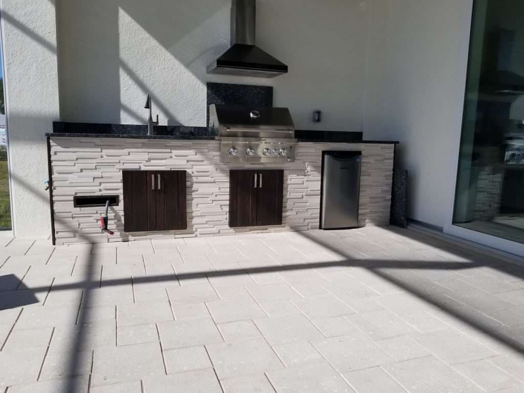 Outdoor kitchen with granite countertop, stainless steel grill, and modern cabinets.