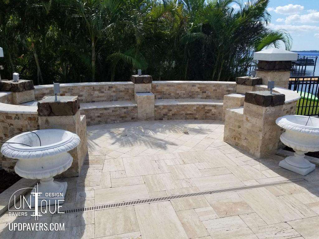 Elegant outdoor seating area with stone benches, surrounded by palm trees and water view.