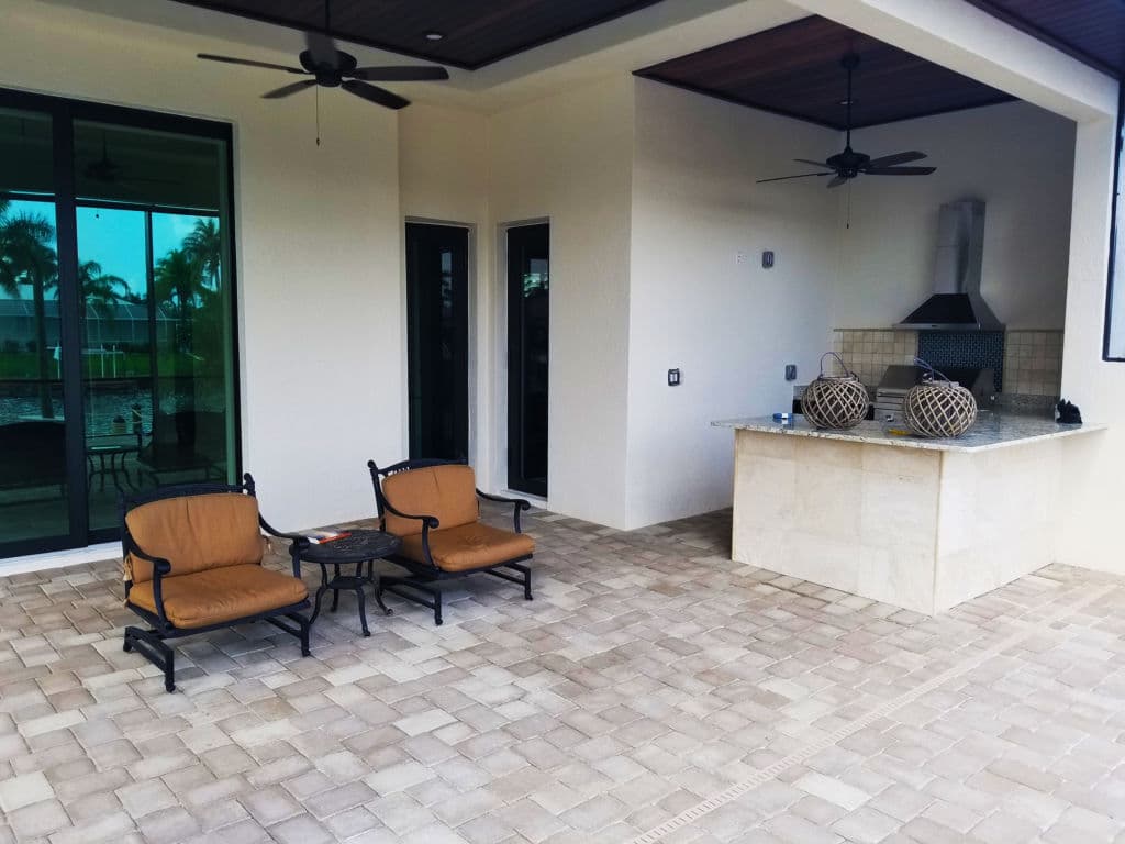 Modern patio with seating, outdoor kitchen, and sleek design in tropical setting.