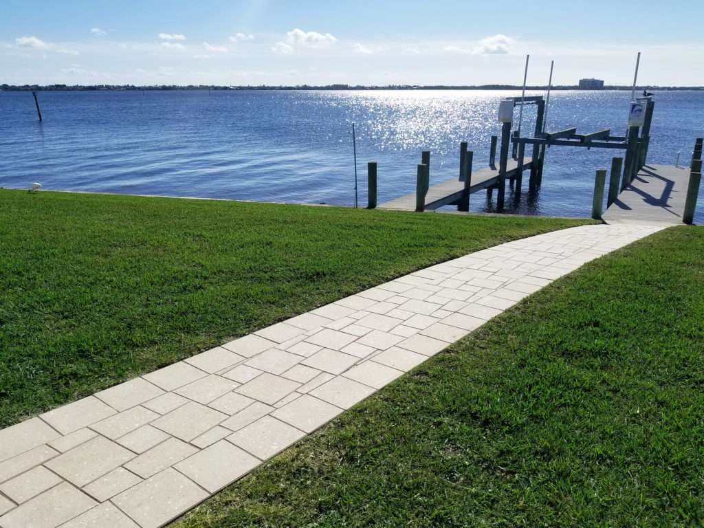 Scenic view of a walkway leading to a dock by a tranquil water body under a sunny sky.