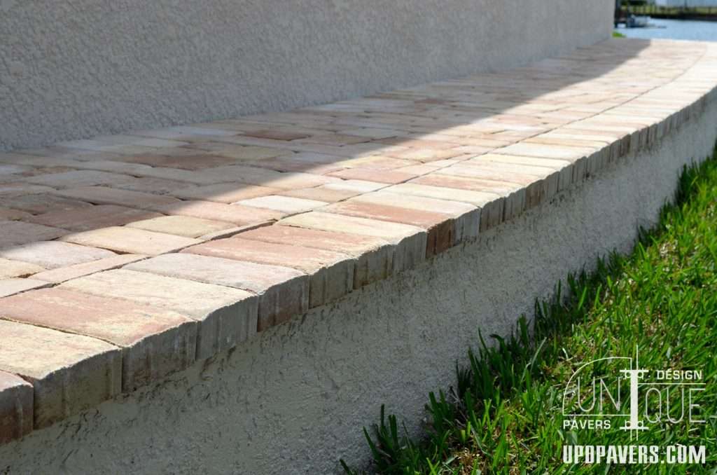 Paver walkway design with textured bricks alongside a grassy edge. Unique landscaping feature.