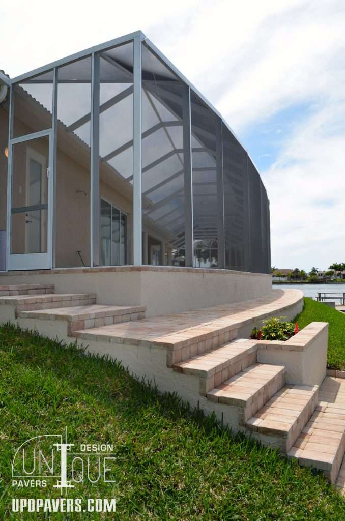 Modern outdoor patio with screened enclosure and landscaped steps leading to water view.