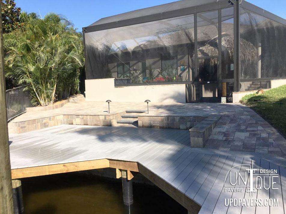 Contemporary outdoor deck with screened enclosure and tropical landscaping. Relaxation area by water.