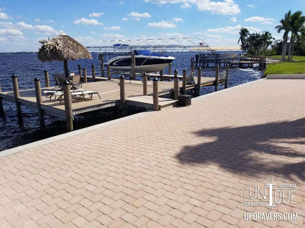 Scenic waterfront dock with boat, paver walkway, and gazebo overlooking calm water.