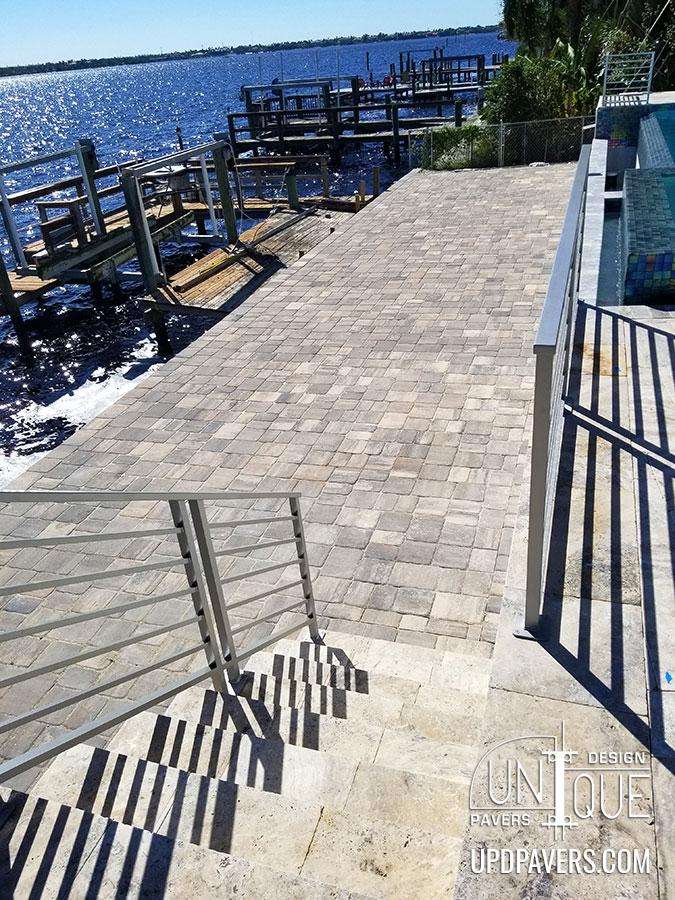 Paver walkway leading to water with docks and serene lake view. Ideal outdoor design.