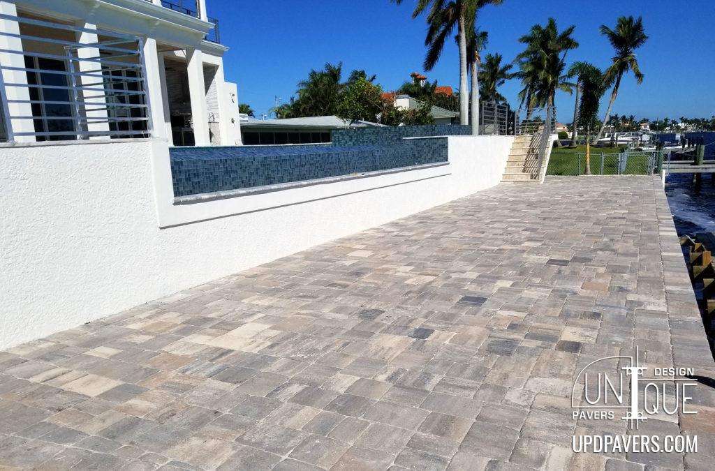Elegant waterfront patio with paver stones and palm trees, ideal for outdoor relaxation.